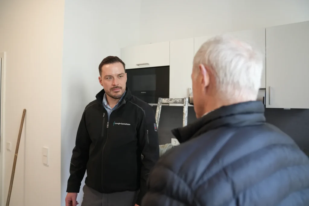 Energieberater im Gespräch mit einem Kunden in einer Wohnung während der Sanierung