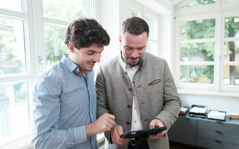Zwei Energieberater betrachten gemeinsam Daten auf einem Tablet