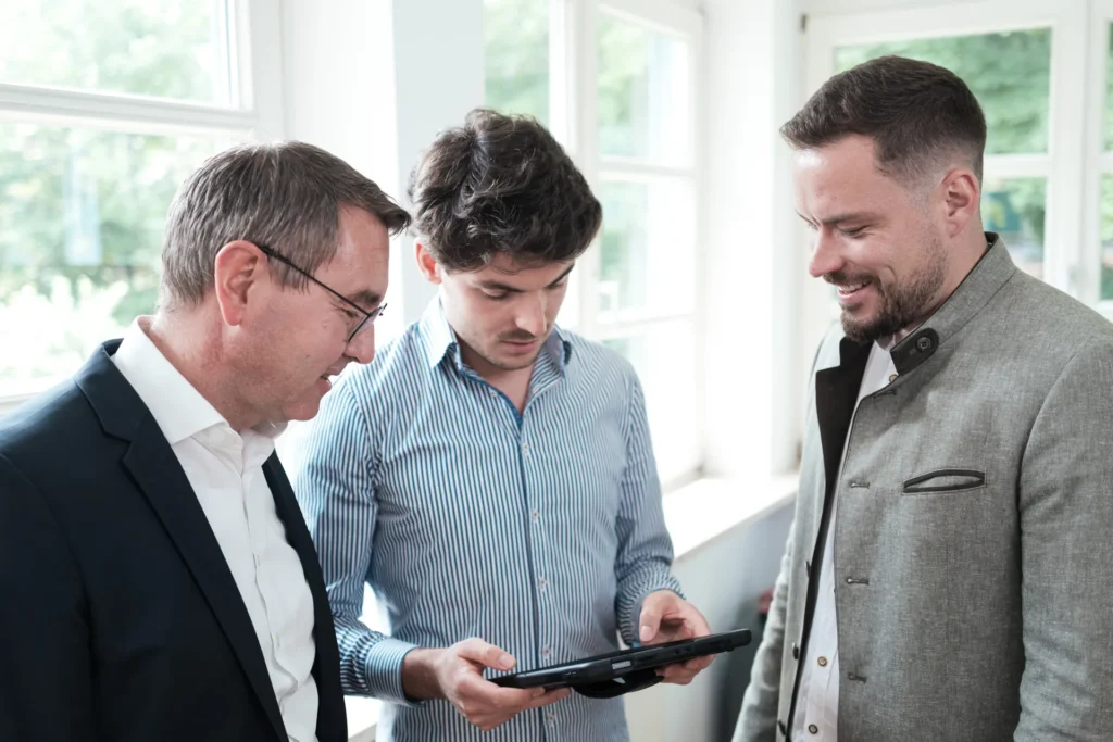 Drei Männer besprechen Ergebnisse auf einem Tablet