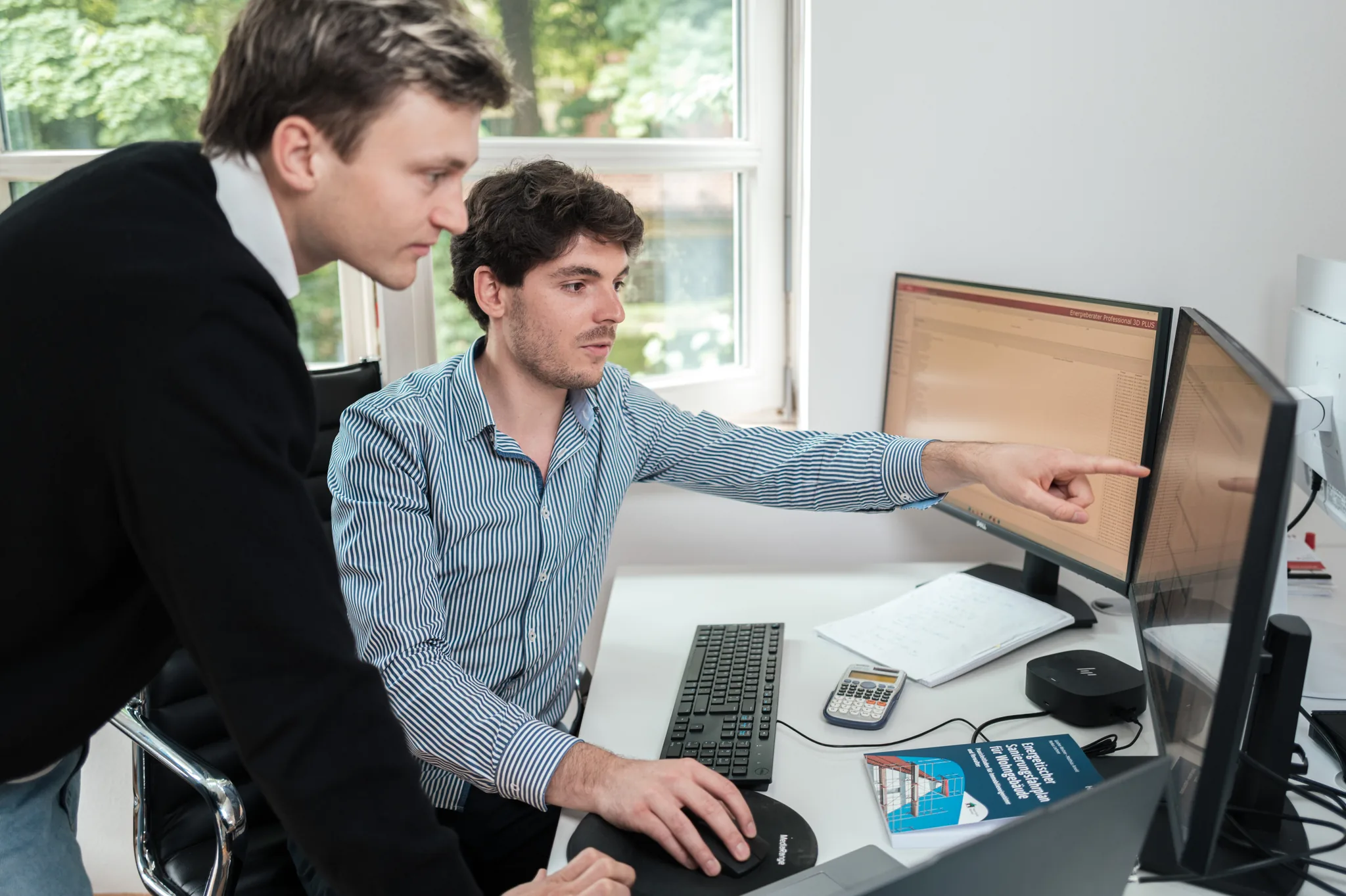 Zwei Energieberater bei der energetischen Berechnung am Doppelmonitor