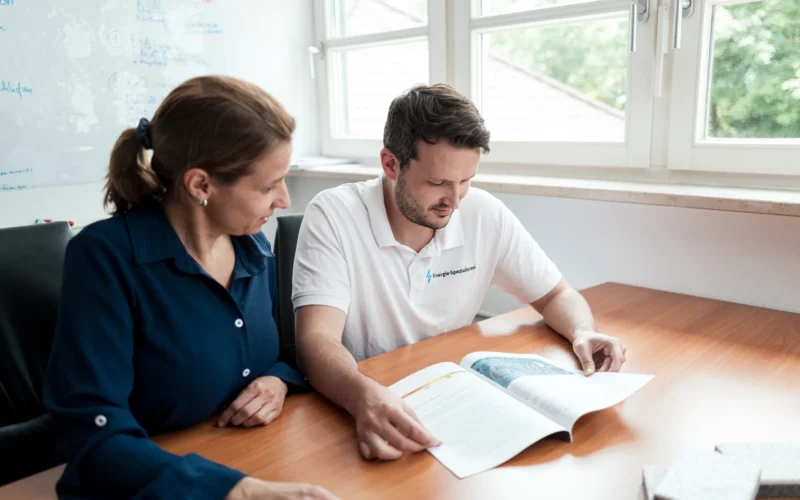 Energieberater geht mit einer Kundin den Beratungsbericht durch