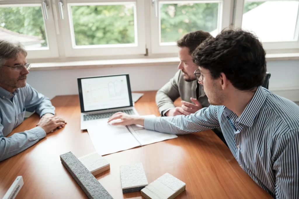 Drei Personen besprechen einen Sanierungsfahrplan am Laptop
