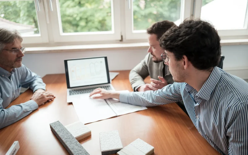 Drei Personen besprechen einen Sanierungsfahrplan am Laptop