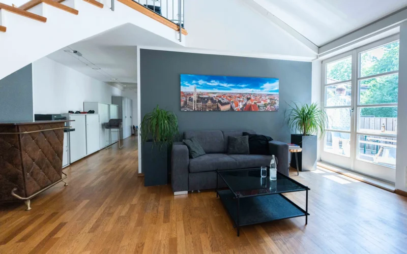 Empfangsbereich des Münchner Büros mit Sofa und Stadtpanorama an der Wand