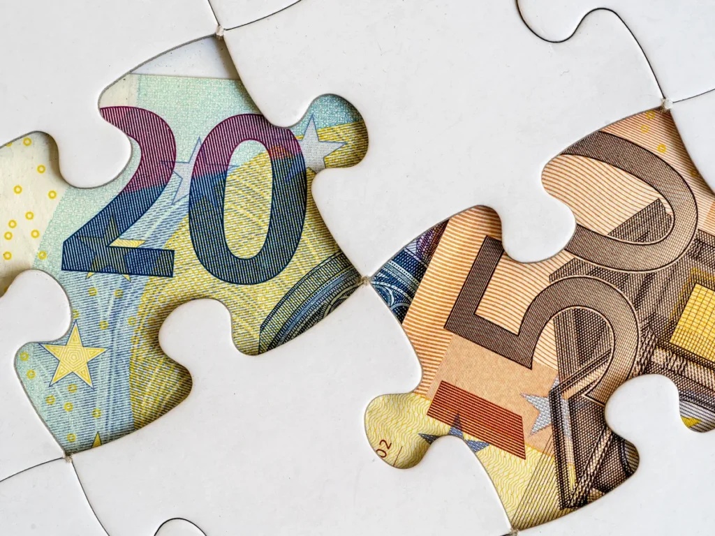 Zwei Puzzleteile aus Euro-Geldscheinen fügen sich zusammen