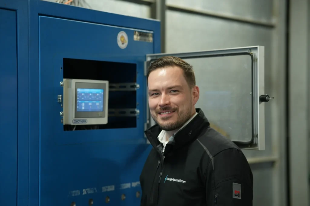 Energieberater vor dem geöffneten Schaltschrank einer Heizungsanlage