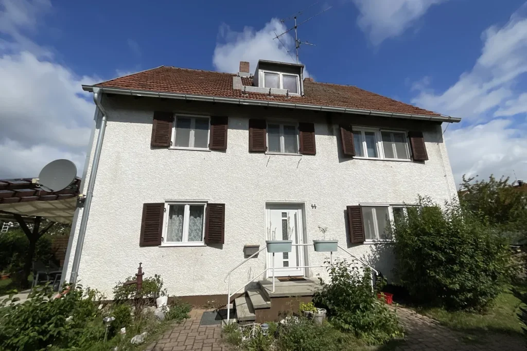 Einfamilienhaus mit Klappläden und rotem Ziegeldach, Außenansicht von der Straße