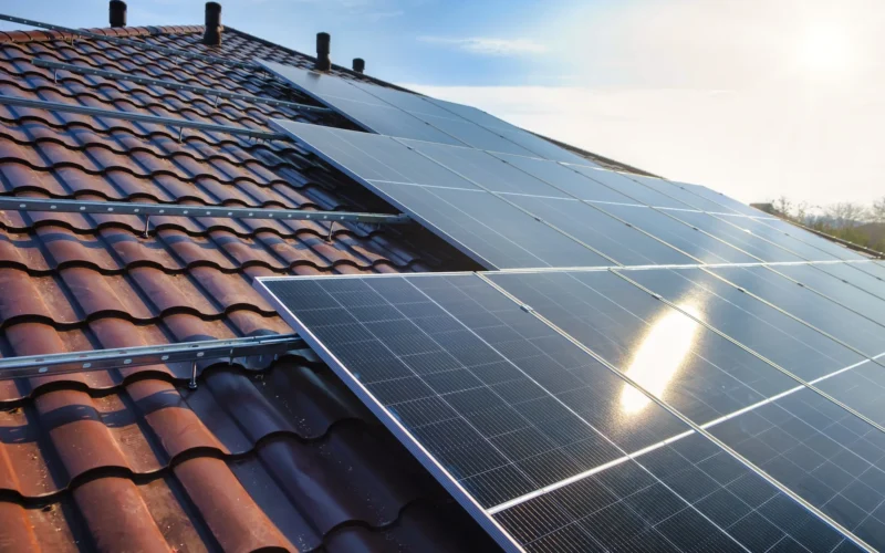 Photovoltaikmodule mit Montageschienen auf einem Ziegeldach im Gegenlicht