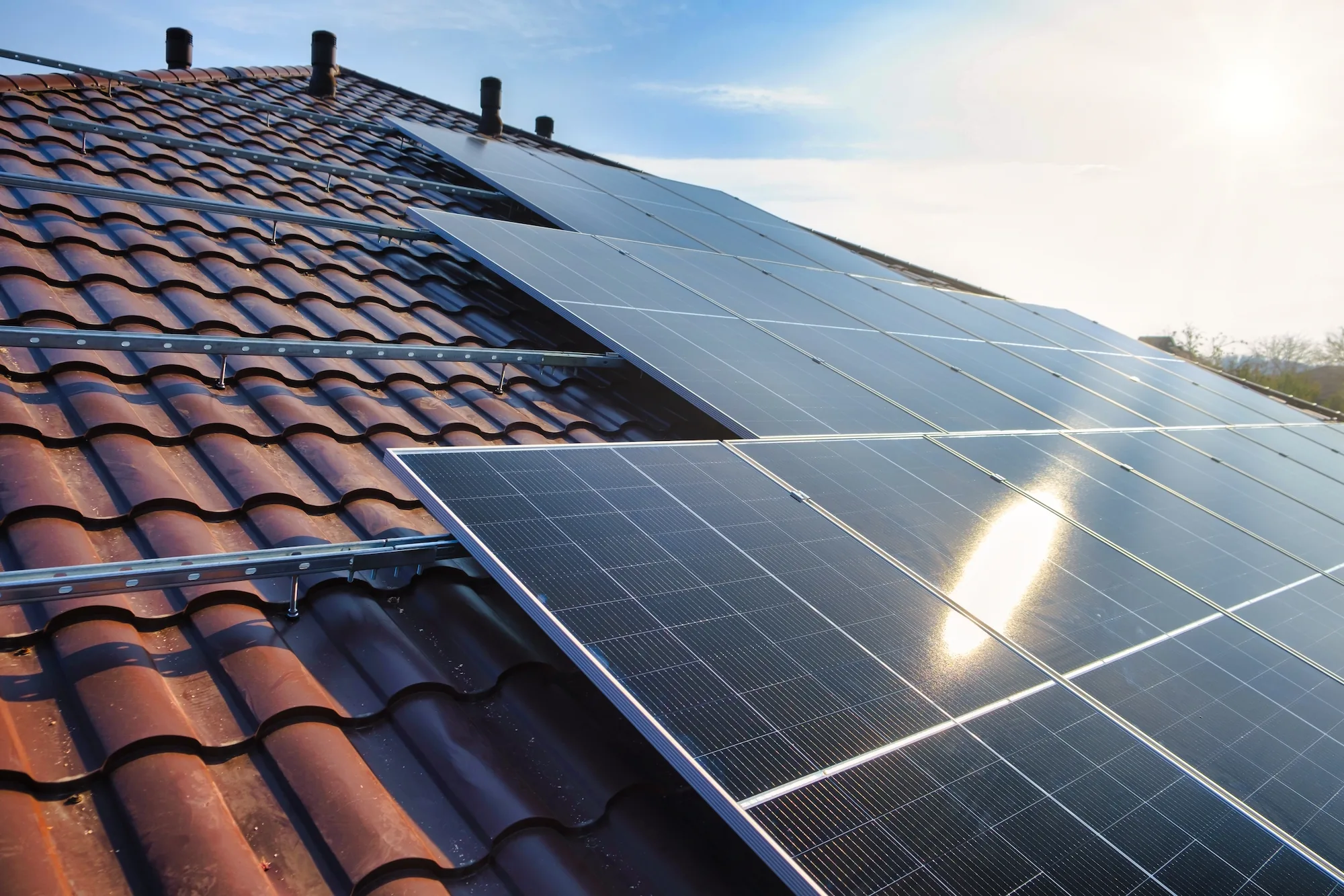 Photovoltaikmodule mit Montageschienen auf einem Ziegeldach im Gegenlicht