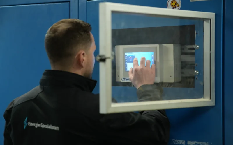 Energieberater stellt die Regelung einer Heizungsanlage am Touchdisplay im Schaltschrank ein